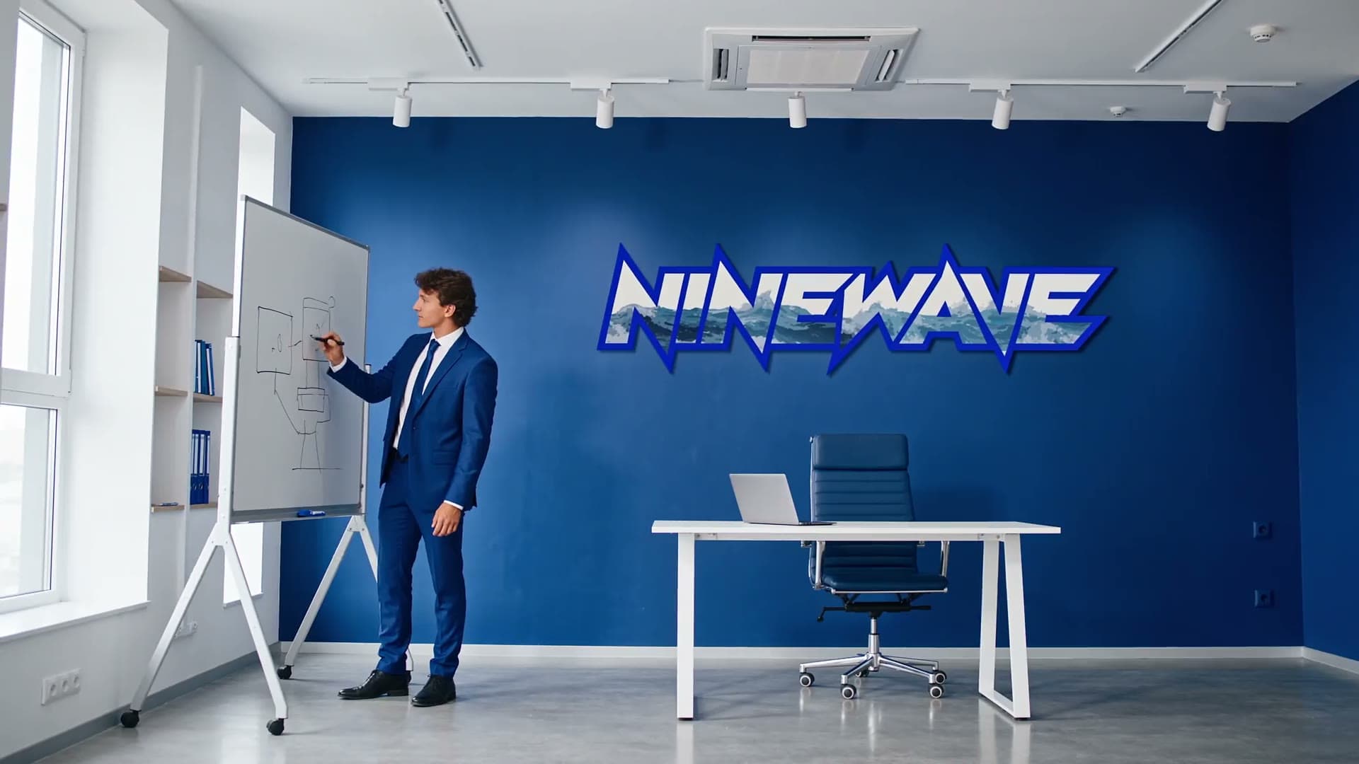 A Ninewave studio film frame: a whiteboard session in front of the Ninewave wall sign